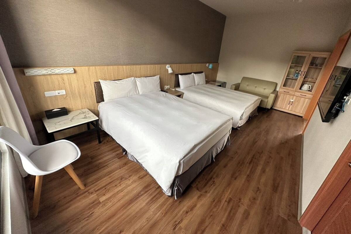 Hotellihuone, jossa on kaksi sÀnkyÀ, työpöytÀ, tuoli, televisio ja kaappi.