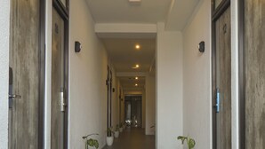 A hallway with doors numbered 10 to 12, potted plants, and a tiled floor.