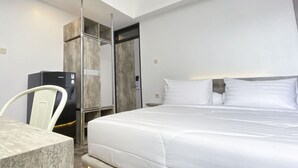 A modern hotel room with a large bed, a desk, and a minibar.