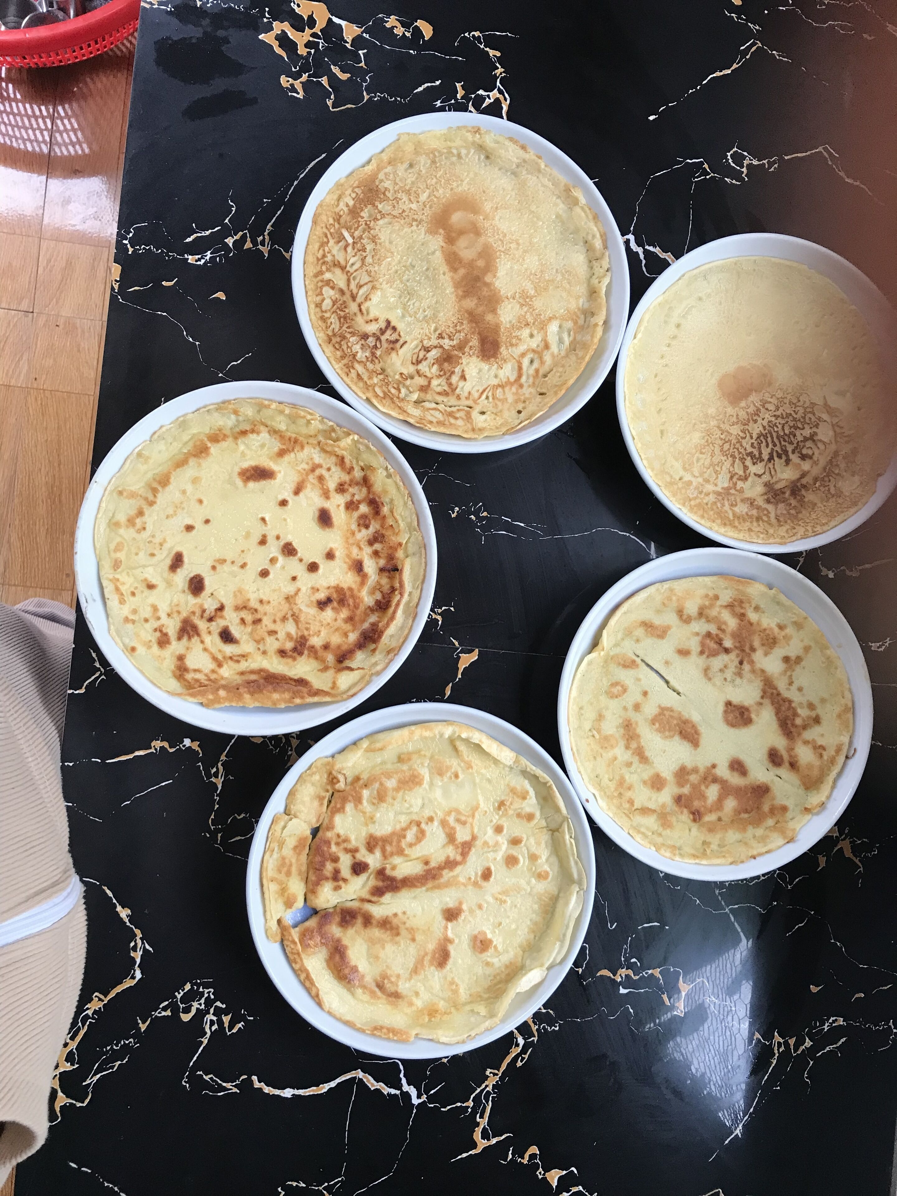 Cinco porciones de crepes sobre una mesa de mármol negro.