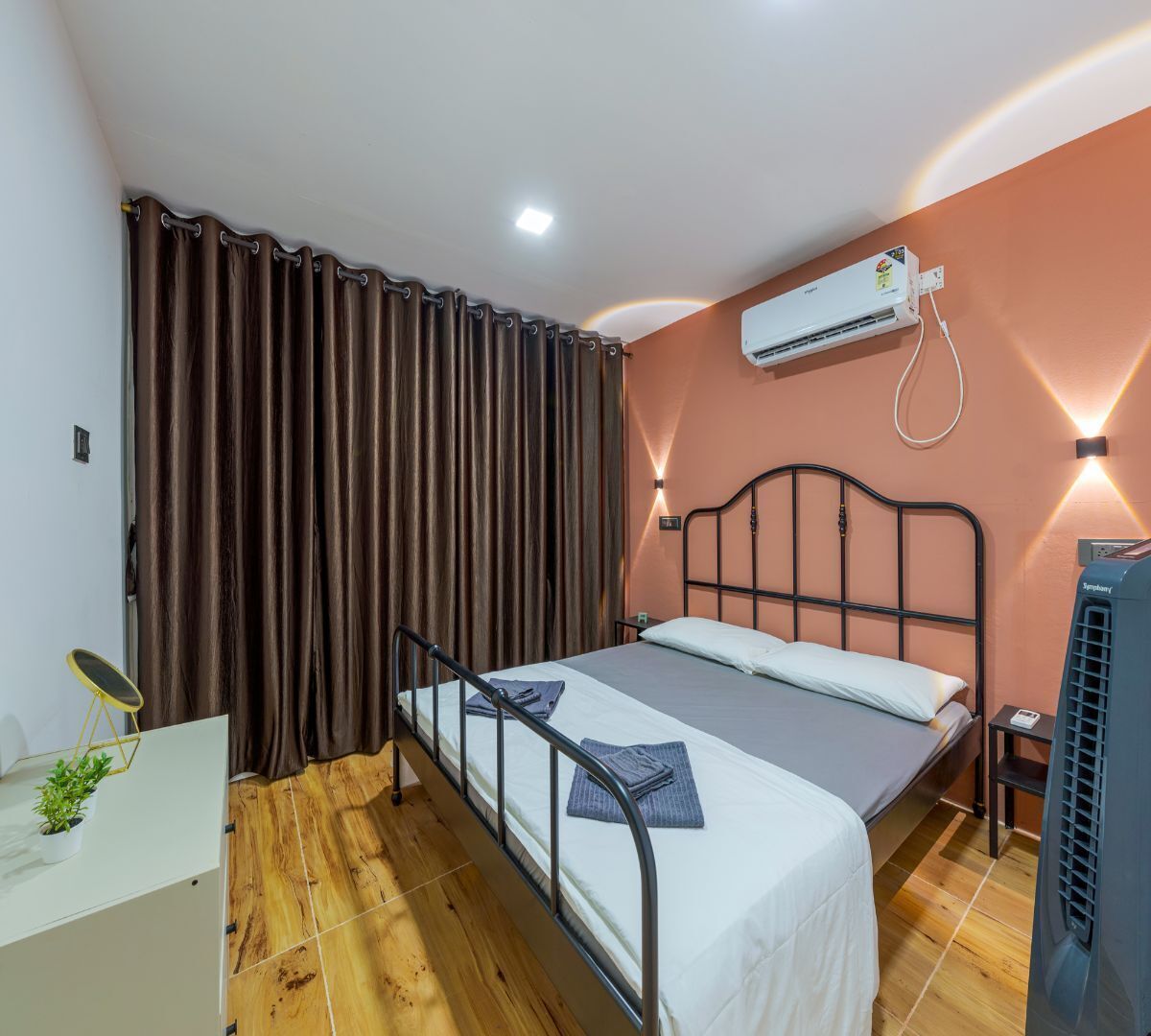 Een slaapkamer met een bed, nachtkastje, airconditioning en een kamerplant.