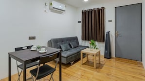A compact living space with a sofa, a dining table, and a small coffee table. - Aalayah Stays (Devgad)