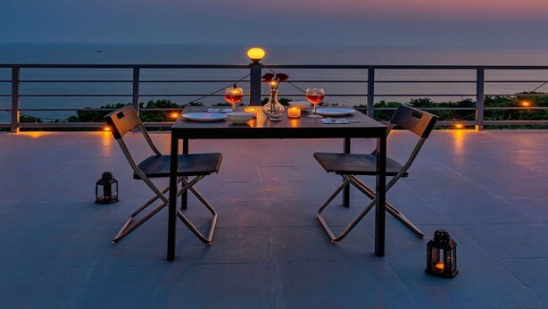 A table set for two with a view of the sea at dusk. - Aalayah Stays (Devgad)