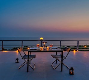 A table set for two with a view of the sea at dusk.