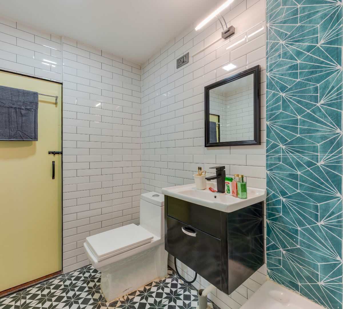 A bathroom with white subway tiles, a black sink, a mirror, and a patterned wall.