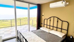 A bedroom with a bed, a window, a balcony, and an air conditioning unit. - Aalayah Stays (Devgad)