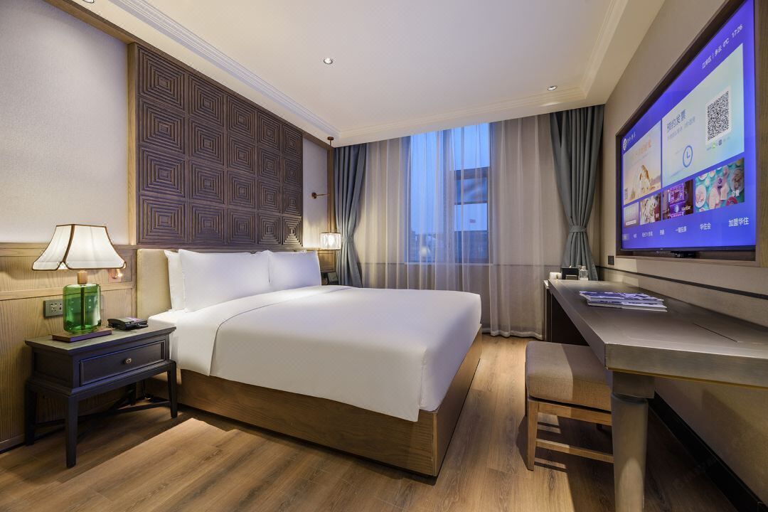 Habitación de hotel con una cama grande, un escritorio, una televisión y vistas a la ciudad.