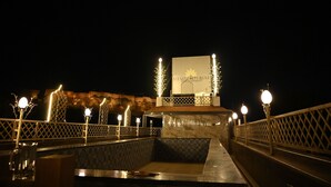 A night view of a hotel with a prominent sign reading "STAMPPERMERK HOTEL & BANQUETES" and a well-lit outdoor area with a checkered floor and railing. - The Shah Imperial (Gwalior)