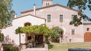 Un bâtiment traditionnel avec un chemin de pierre menant à un patio doté d’un espace salon extérieur.