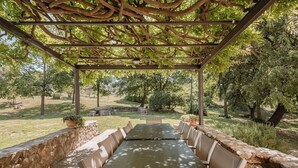 Un espace extérieur aménagé, abrité et doté de murs en pierre et d’une pergola.