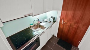 A compact kitchen with a stove, sink, and white cabinets.