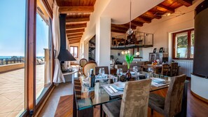 A dining area with a glass table, chairs, and a view of the sea. - Superattico Villanova 4 Emma Villas (Cagliari)
