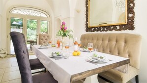 A dining area with a table set for four, a sofa, and a mirror on the wall.