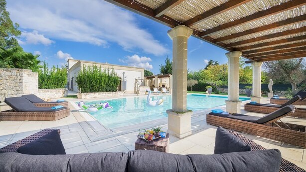 A pool area with lounge chairs, a swan float, and a pergola.