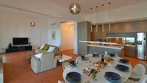 A modern living room with a flat-screen TV, a sofa, and a dining area set for a meal. - Villa Salone 8 Emma Villas (Pollina)