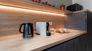 A kitchen counter with a coffee maker, a toaster, a plate of pastries, and a red sign above. - C-Apartment A Scrovegni luxury suite (Padova)