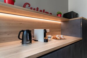 En køkkenbordplade med en kaffemaskine, en brødrister, et fad med kager og et rødt skilt over.
