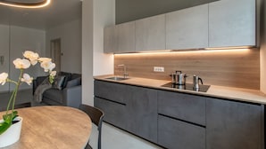 A modern kitchen with a wooden countertop, grey cabinets, and a built-in oven. - C-Apartment A Scrovegni luxury suite (Padova)