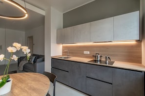 Et moderne køkken med en træbordplade, lysegrå skabe og en indbygget ovn.