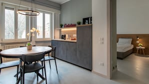 A modern kitchen with a dining area, a built-in bench, and a bed with a headboard. - C-Apartment A Scrovegni luxury suite (Padova)