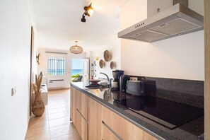 Een moderne keuken met een kookplaat, koffiezetapparaat en uitzicht op zee.