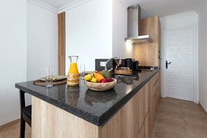 Eine moderne Küche mit Granitarbeitsplatte, Holzausbau und integriertem Herd, sowie einer Schale mit Obst.