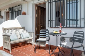 Relax in this serene outdoor seating area with a bench and chairs, perfect for enjoying a drink.