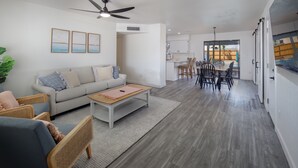 Een moderne woonkamer met een bank, stoelen, een salontafel en een eethoek met stoelen en een tafel.