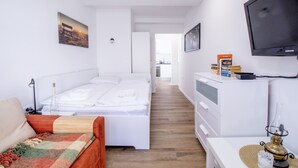 Quarto de hotel com cama, escrivaninha, televisão e vista para o corredor.