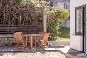 An outdoor patio with a wooden table and chairs, a stone wall, and a wooden fence. - BLED LAKE HOUSE - Apartment LAKE (Radovljica)