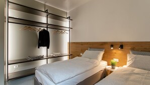 A modern bedroom with a bunk bed, a wooden headboard, bedside tables, and a clothing rack.