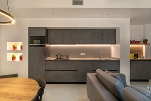 A modern kitchen with integrated appliances, a dining area with a wooden table and chairs, and a built-in sofa.