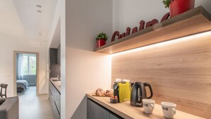 A modern kitchen with a wooden countertop, a kettle, a toaster, and a potted plant.