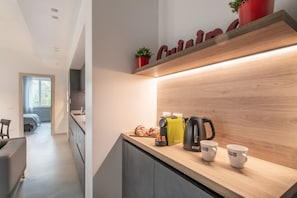Et moderne køkken med træbordplade, elkedel, brødrister og en potteplante.