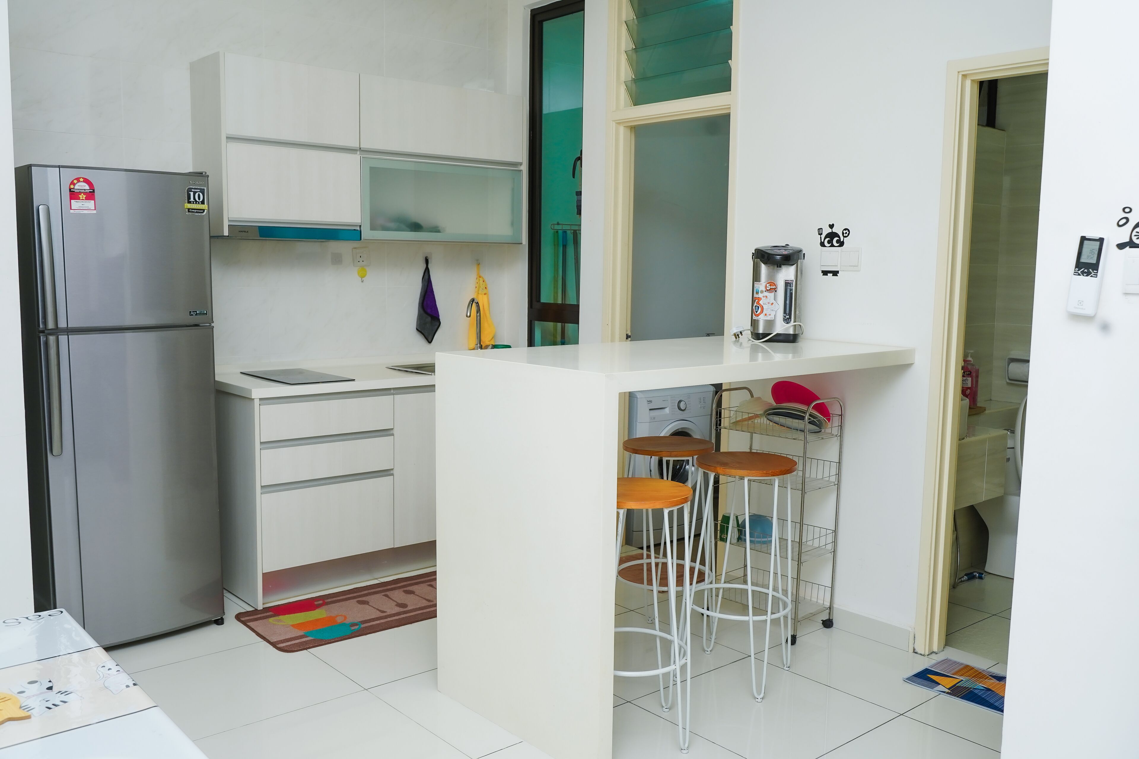 A compact kitchen with a refrigerator, a small countertop, and a bar stool area.