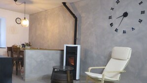 Una sala de estar moderna con chimenea, un reloj en la pared y un sillón cómodo.