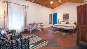 A cozy room with a bed, a sofa, a small table, and a window with curtains. - MANJARI RESORT (Ghansyali)