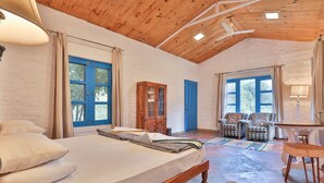 A spacious room with a large bed, a wooden ceiling, and a view of the outdoors through multiple windows. - MANJARI RESORT (Ghansyali)