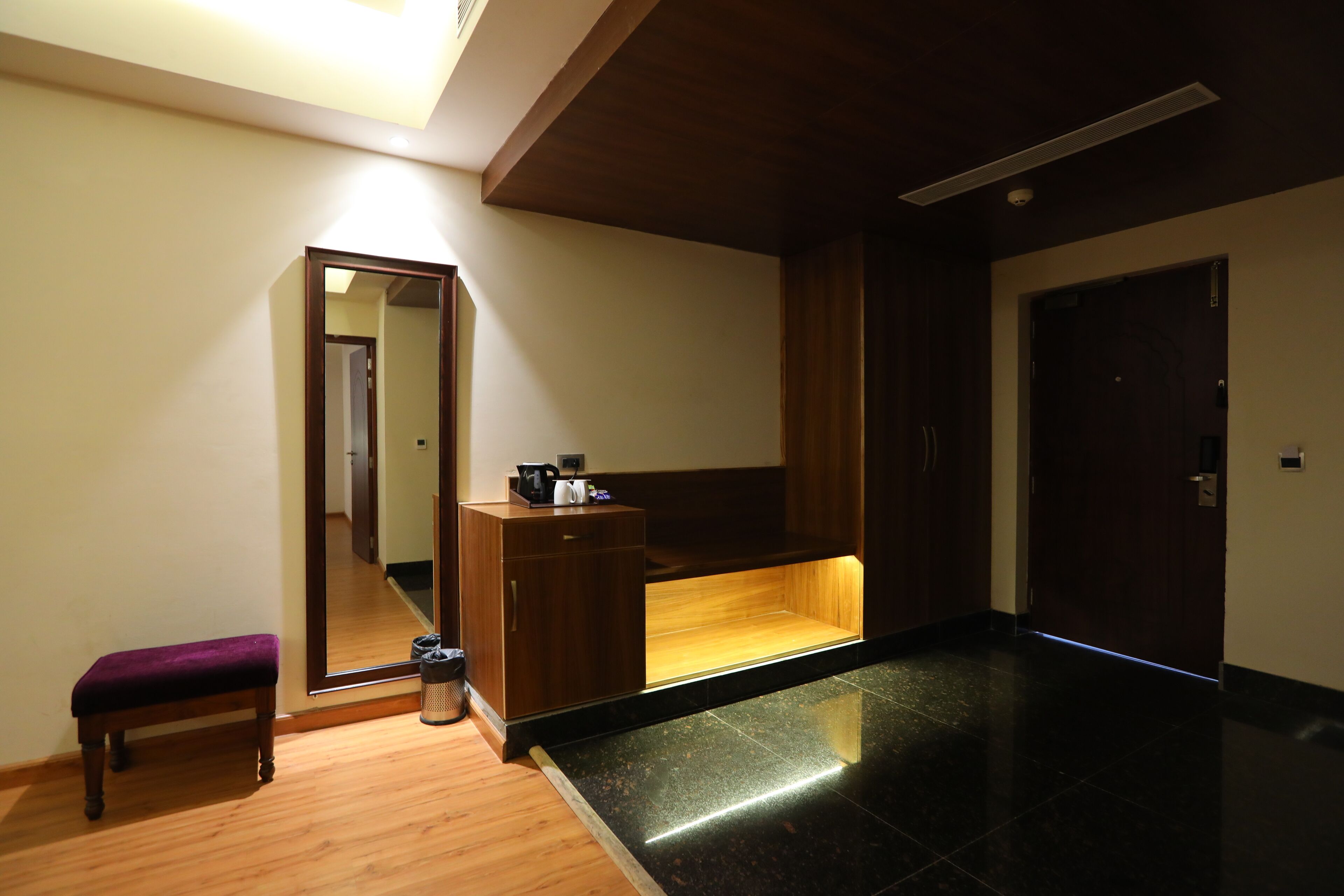 A modern bathroom with a wooden bench, a mirror, a vanity with a sink, and a door.