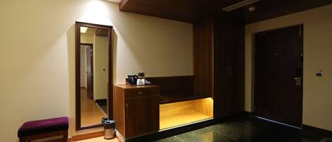 A modern bathroom with a wooden bench, a mirror, a vanity with a sink, and a door.