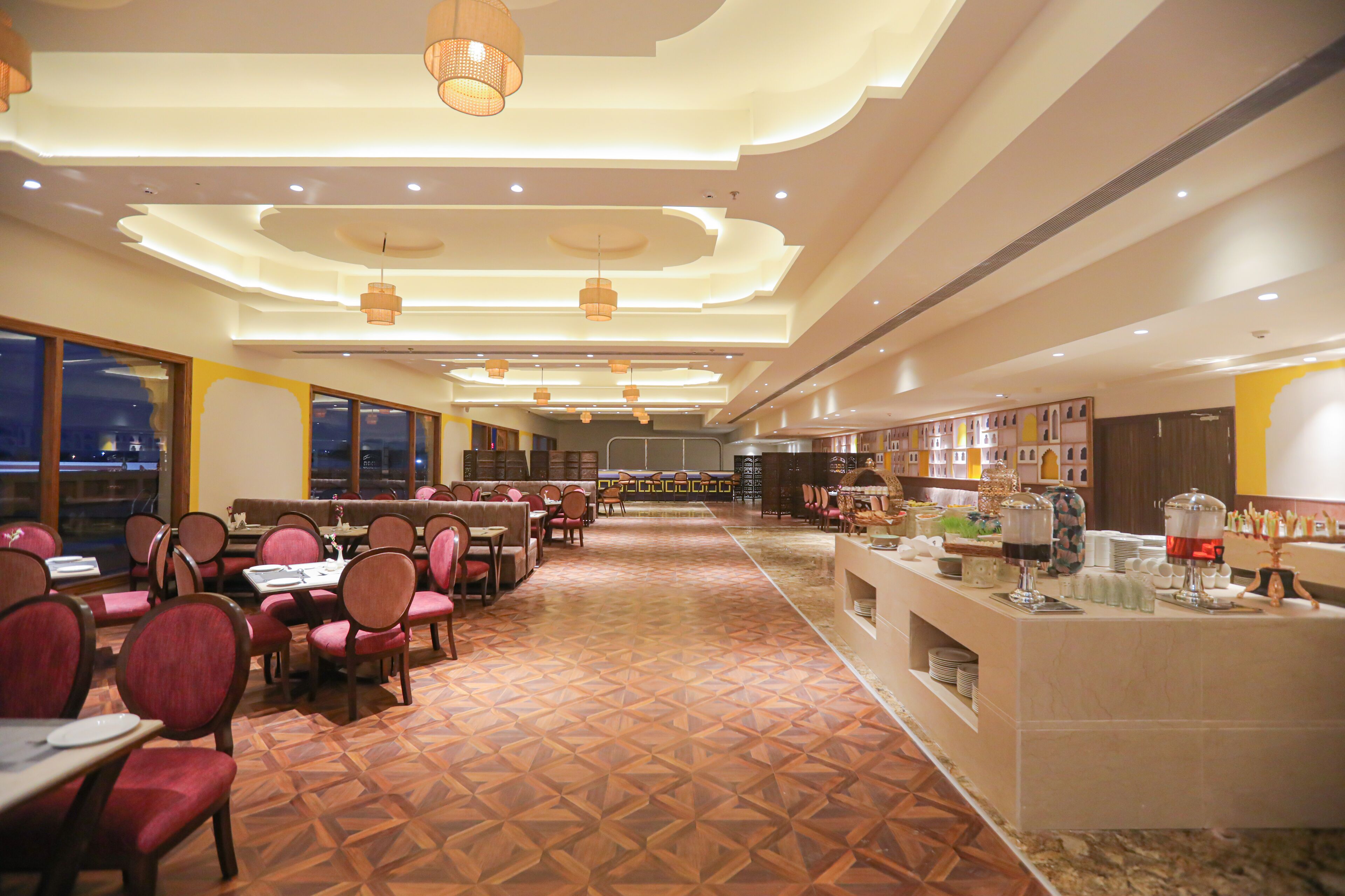 A spacious restaurant with a long counter, multiple dining tables, and chairs.