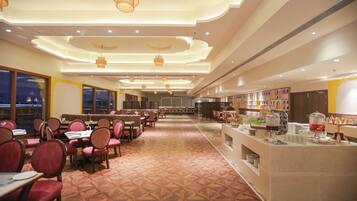 A spacious restaurant with a long counter, multiple dining tables, and chairs.