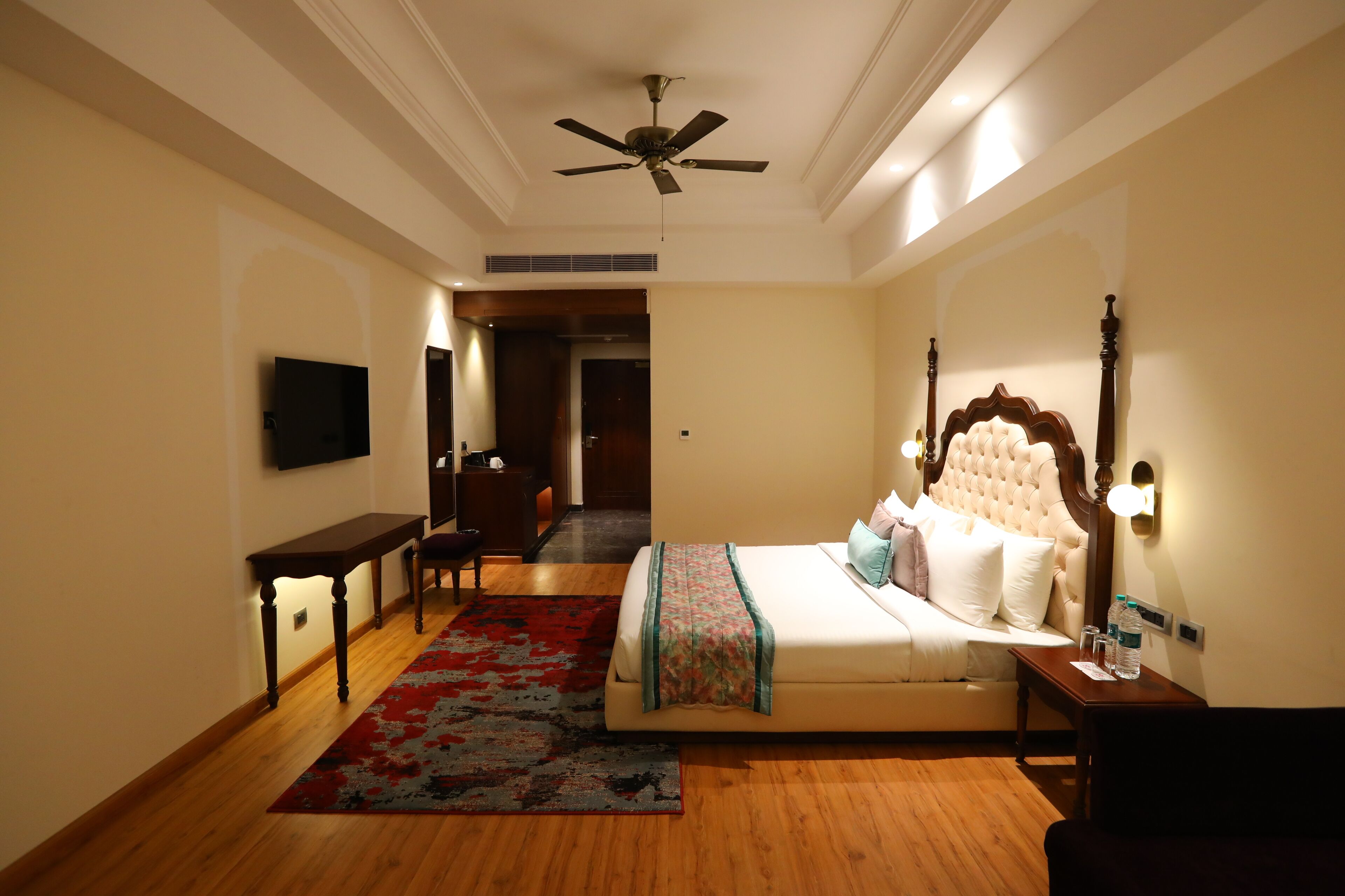 A hotel room with a bed, bedside table, nightstand, and a ceiling fan.