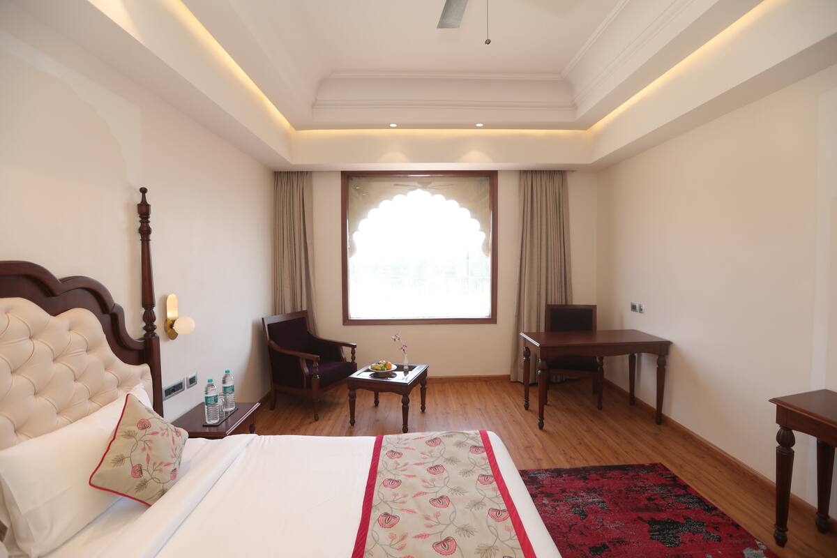 Een hotelkamer met een bed, bureau, stoel, televisie en raam met gordijnen.