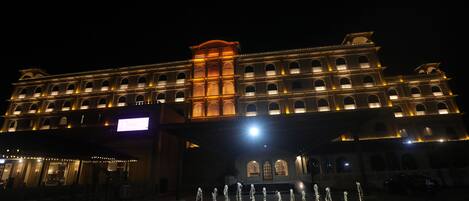 Un hotel grande con varios pisos, una fuente central y ventanas iluminadas.