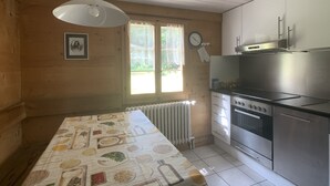 Una cocina con una mesa de comedor, estufa y ventana con cortinas.