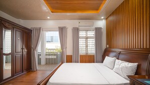 Ein Hotelzimmer mit einem großen Bett, einem Holzkopfende und Blick ins Freie durch ein Fenster.