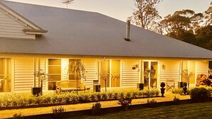 Uma casa de dois andares com varanda da frente, um banco e entrada para carros.