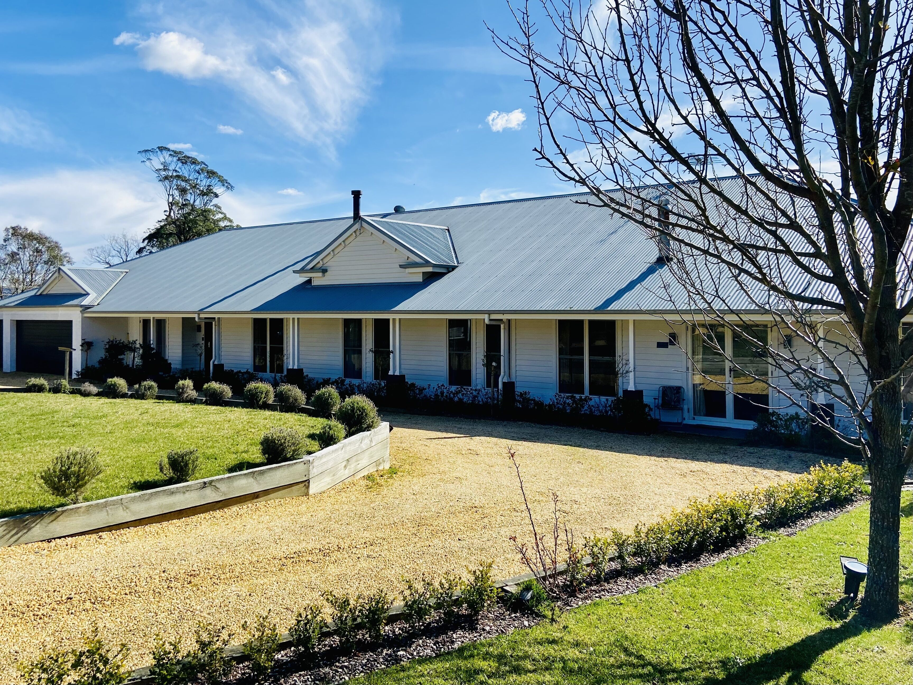 A two-story house with a covered porch, a gravel driveway, and a well-maintained lawn.