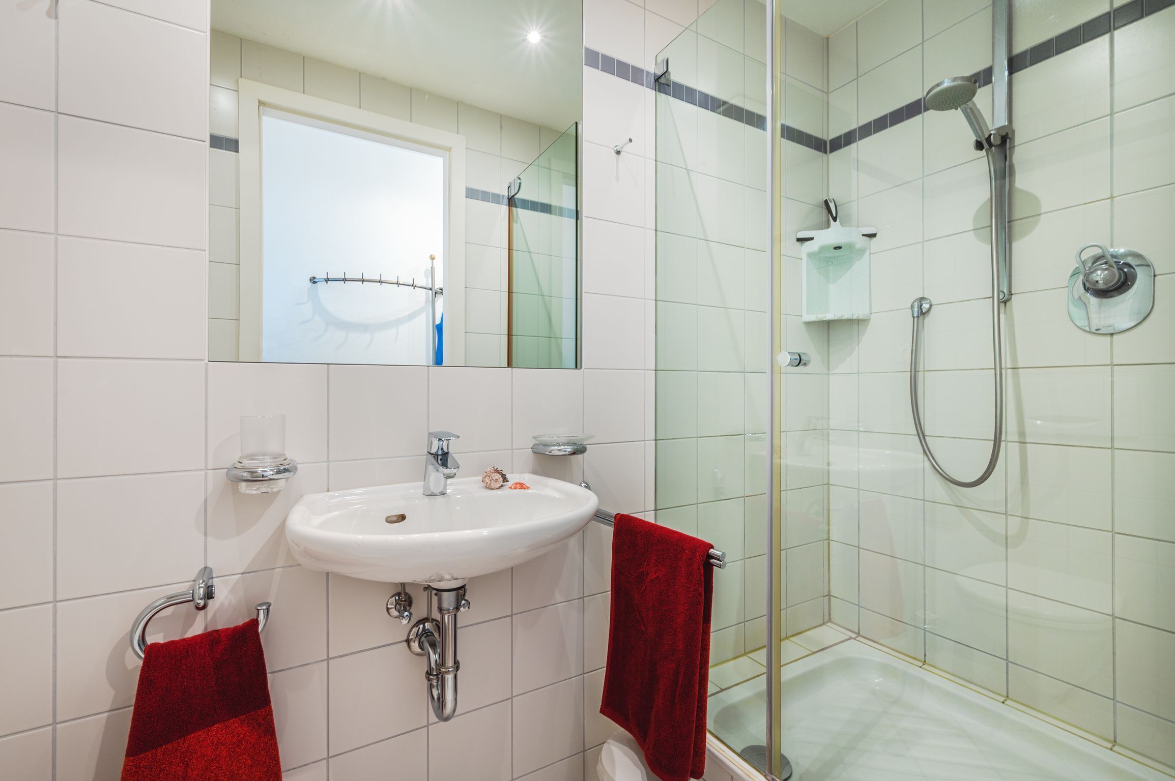 A bathroom with a white sink, a glass shower enclosure, and a mirror above the sink.